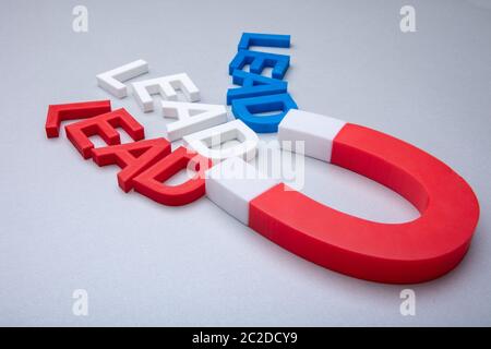 Person's Hand Holding Horseshoe aimant qui attire les câbles de couleur des lettres sur fond blanc Banque D'Images