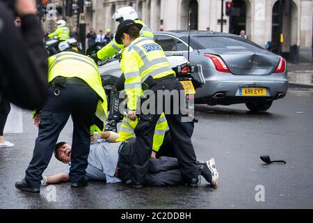 La police a arrêté un homme après qu'il s'est présenté devant la voiture du Premier ministre Boris Johnson (en arrière-plan avec une bosse) alors qu'il quittait le Parlement, Westminster. L'homme, qui manifestait au sujet de l'opération de la Turquie contre les rebelles kurdes dans le nord de l'Irak, a été emmené au Palais de Westminster par des officiers. Banque D'Images