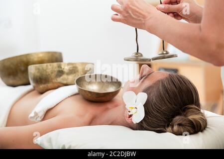 Gros plan d'une jeune femme se détendant avec des bols chantants et des cymbales dans le spa Banque D'Images