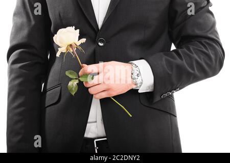 Un gros plan d'un jeune homme en costume tenant une fleur, isolé sur fond blanc. Banque D'Images