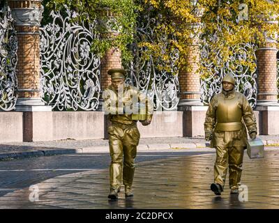 Hommes peints en or habillés comme la statue vivante attractions touristiques marchant devant la clôture en métal ornée de Mikhaïlovsky Garden, Saint-Pétersbourg, Russie Banque D'Images