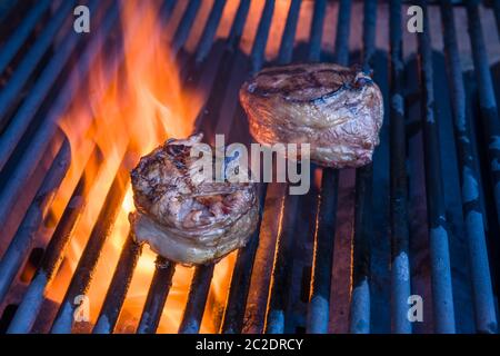 Une paire de filet mignon enveloppé de bacon et cuisant un grill avec une flamme Banque D'Images