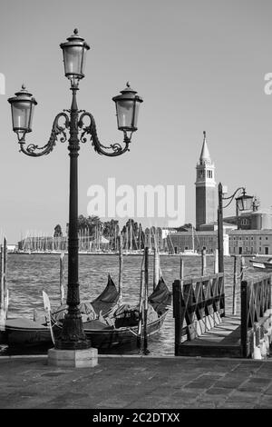 Les gondoles de Venise amarrées près du front de mer Riva degli Schiavoni avec de vieux feux de rue et l'église de San Giorgio Maggiore en arrière-plan. B Banque D'Images