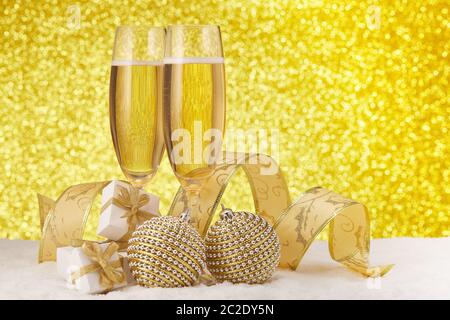 Deux verres à champagne, des boîtes-cadeaux et des décorations de Noël sur une surface enneigée sur un fond doré festif. Copier l'espace. Noël an Banque D'Images