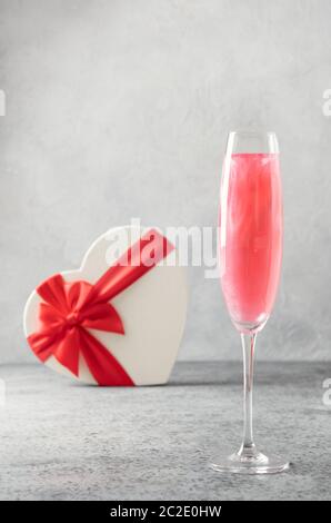 Vin mousseux pailleté comestible scintillant scintillant dans deux verres avec cadeau en forme de coeur sur gris. Banque D'Images