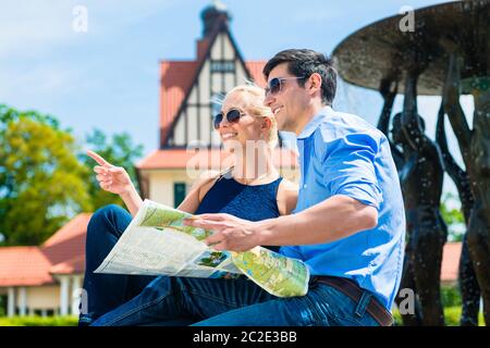 Portrait d'un jeune couple souriant explorant l'endroit tenant la carte entre les mains Banque D'Images