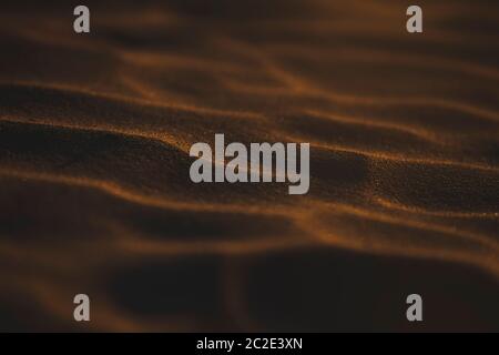 Motifs dans le sable sur une plage avec une lumière de moody au coucher du soleil. Banque D'Images