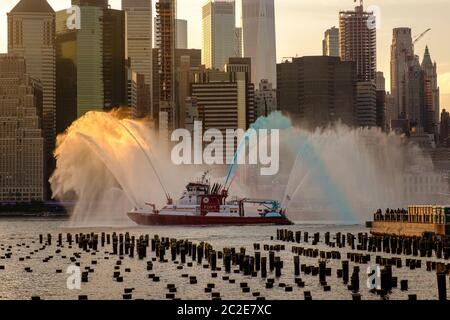 Le bateau FDNY pulvérise de l'eau rouge, blanche et bleue avant le feu d'artifice du 4 juillet de Macy Banque D'Images