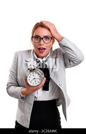 Belle jeune femme d'affaires vêtu d'un costume avec une horloge avec expression choquée, isolé sur un fond blanc. Banque D'Images