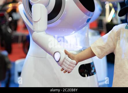 Robot sympathique qui se secoue les mains avec un petit garçon, technologie SMART robot concept Banque D'Images