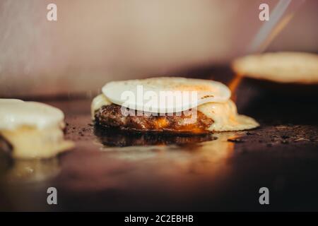 Faire cuire le hamburger en ajoutant la sauce sur le fromage à la crème. Trois hamburgers. Banque D'Images