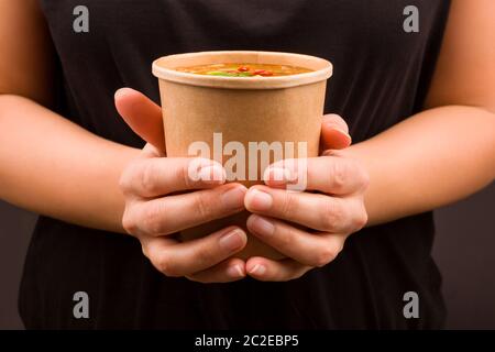 Belle femme de manger sur le pouce. Soupe aigre et piquante dans la tasse à emporter. Cousine traditionnelle asiatique. Banque D'Images