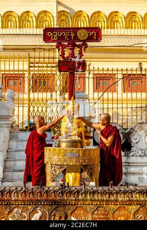 Des moines bouddhistes versant de l'eau sur UNE statue de Bouddha à la Pagode Shwedagon, Yangon, Myanmar. Banque D'Images