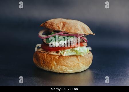 Circulaire Burger. Hamburger au fromage avec viande grillée, fromage, salade et rondelles d'oignon. Gros plan de délicieux hamburgers maison frais sur fond bleu écorce Banque D'Images