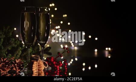 Deux verres avec champange, branche de sapin avec décorations et biscuits au pain d'épice sur fond sombre avec guirlande lumineuse LED. Nouvelle année et Christ Banque D'Images