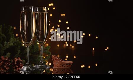 Deux verres avec champange, sapin avec décoration, boîte cadeau sur fond sombre avec guirlande lumineuse LED. Nouvel an et Noël. Banque D'Images