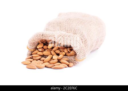 Gros plan du sac de jute renversé d'amandes, isolé sur fond blanc. Banque D'Images