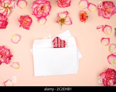 Enveloppes en papier blanc et rouge deux coeurs sculptés au milieu des rosebuds, vue du dessus, toile de fête Banque D'Images