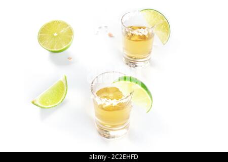 Tequila shots d'or avec des tranches de lime et de salé sur jantes blanches avec copyspace Banque D'Images