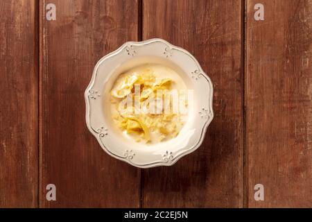 Tortellini italien servi avec une sauce crème et parmesan, passage tourné sur un fond rustique en bois foncé Banque D'Images