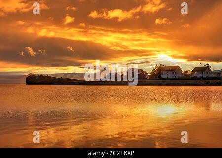 Un beau coucher de soleil orange peu après une tempête dans le petit village de pêcheurs de Hofn dans le sud-est de l'Islande. Banque D'Images