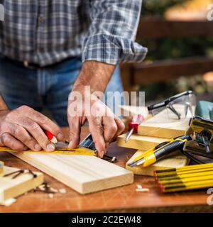 Artisan menuisier adultes avec un crayon et l'équipe de menuisier de tracer la ligne de coupe sur une table en bois. Ménage faire vous-même. Stock photography. Banque D'Images