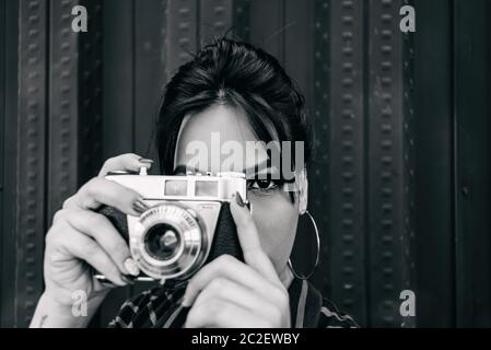 femme avec un appareil photo ancien prenant une photo regardant sa cible. Banque D'Images