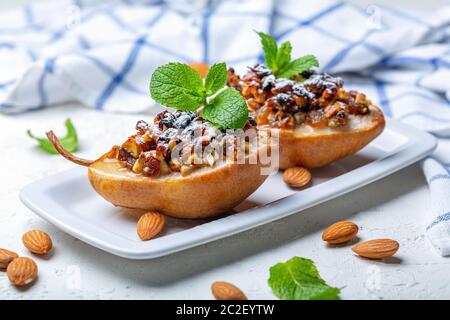 Poires cuites aux raisins secs, aux noix, au miel et à la menthe. Banque D'Images