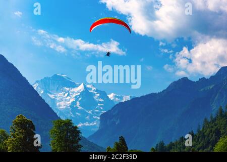 Un parapente survolant Interlaken, important centre touristique dans les Highlands bernois, Suisse. La Jungfrau est visible en arrière-plan Banque D'Images