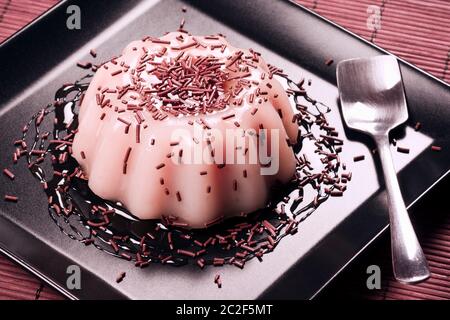 Dessert au lait rose avec goût fraise ou framboise sur assiette noire. Banque D'Images