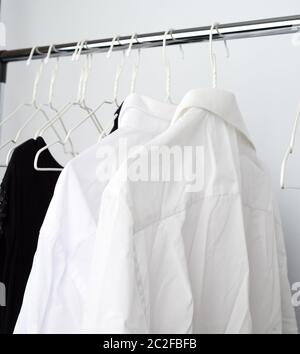 White men's shirts froissé accrochée à un cintre en métal, fond blanc Banque D'Images