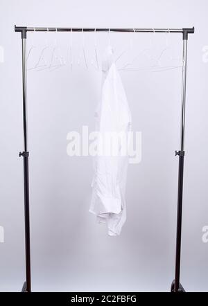 Hommes chemise froissée blanche accrochée à un cintre en métal, fond blanc, concept de la solitude Banque D'Images