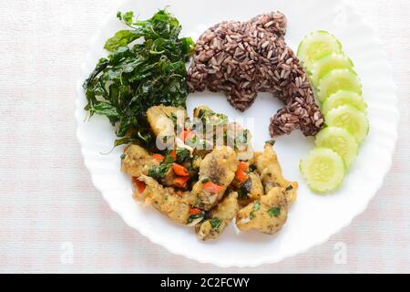 Mélangez le poisson frit au piment et au basilic, servi avec du riz et du concombre cuits à la vapeur, un plat chaud et épicé. Banque D'Images