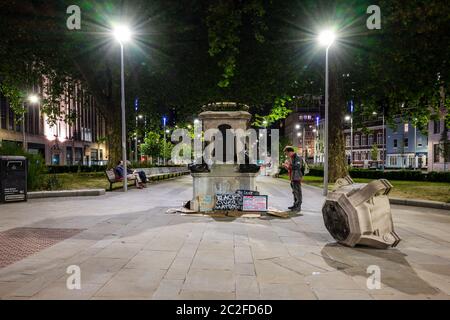 Bristol, Angleterre, Royaume-Uni - 8 juin 2020: Les gens passant le plinthe de la statue renversée du commerçant d'esclaves Edward Colston à Bristol lisent et laissent des placards Banque D'Images