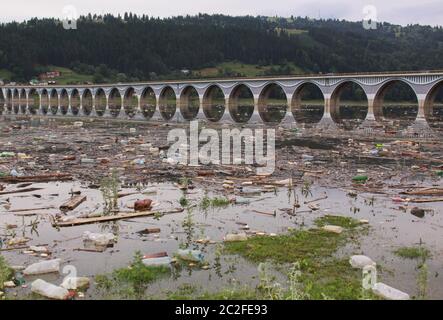 Eau polluée avec des débris de bouteille en plastique au pont au-dessus du lac Bicaz sur le fleuve Bistrita, Roumanie. Destruction de l'environnement causée par l'entrée de déchets Banque D'Images