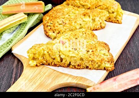 Des scones à la rhubarbe sur parchemin, serviette et d'un bords de la rhubarbe dans le contexte de the wooden board Banque D'Images