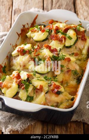 Casserole crémeuse de courgettes de poulet avec bacon en gros plan dans un plat de cuisson sur la table. Verticale Banque D'Images