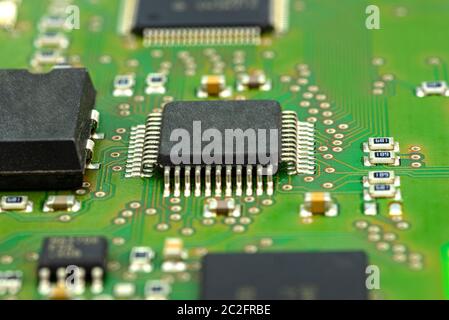 Photo macro du circuit intégré sur une carte de circuit imprimé verte, des résistances visibles et une puce. Banque D'Images