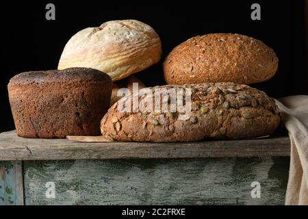 Ensemble de divers petits pains de seigle cuit sur une vieille table en bois, fond noir Banque D'Images