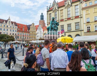 Wroclaw, Pologne - 16 août 2019 : les touristes sur une visite guidée gratuite écoutant un guide en face du monument Aleksander Fredro. Banque D'Images