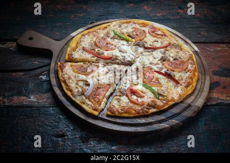 Pizza fraîche et savoureuse avec thon, tomate, paprika et mozzarella isolées sur fond rustique en bois Banque D'Images