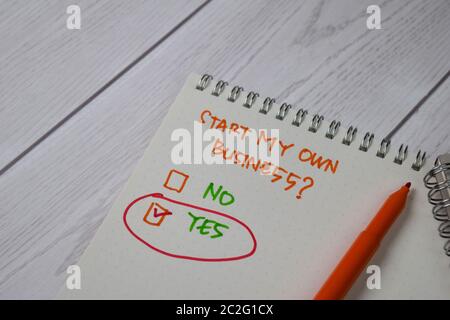 Démarrer mon propre entreprise écrire sur un pense-bête. Supporté par une table en bois isolée de services supplémentaires. Banque D'Images