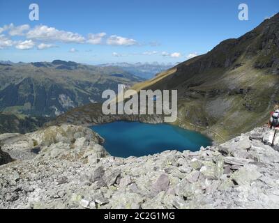 Les sommets des montagnes grises, le coton des nuages et un ciel bleu profond se reflètent dans le lac alpin turquoise ensoleillé Banque D'Images