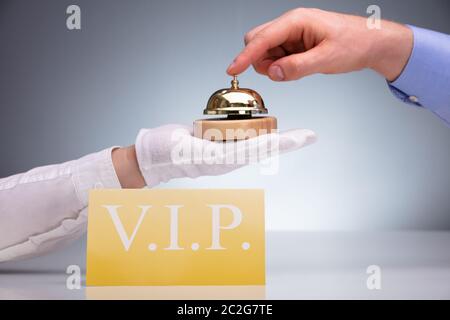 Golden VIP carte sur table en face d'une personne Ringing Service Bell Banque D'Images