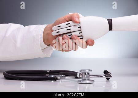 Médecin et le robot se serrer la main sur Stethoscope Banque D'Images