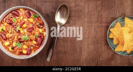 Un panorama de Chili con carne avec nachos, tiré du dessus sur un fond rustique en bois sombre Banque D'Images