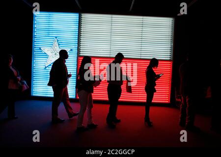 San Antonio Texas Etats-Unis, 25 mars 2016: Les gens qui se tiennent en ligne à l'Institut des cultures texanes sont silhouettés contre un grand fluo rendu d'un drapeau du Texas. ©Bob Daemmrich Banque D'Images