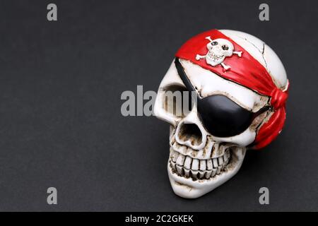 Crâne pirate avec foulard de tête rouge sur fond sombre Banque D'Images