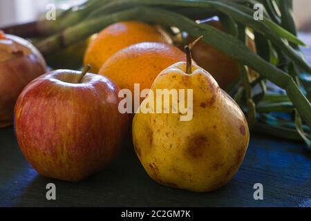 Une poire et quelques autres fruits sur une table bleue Banque D'Images