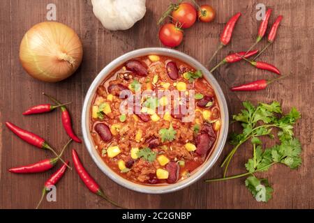 Chili con carne, tourné à partir de ci-dessus, sur un fond de bois rustique foncé avec des ingrédients Banque D'Images